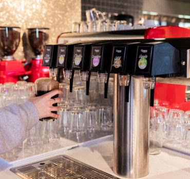 Schenktoren met meerdere tappen achter een bar, met een glas eronder